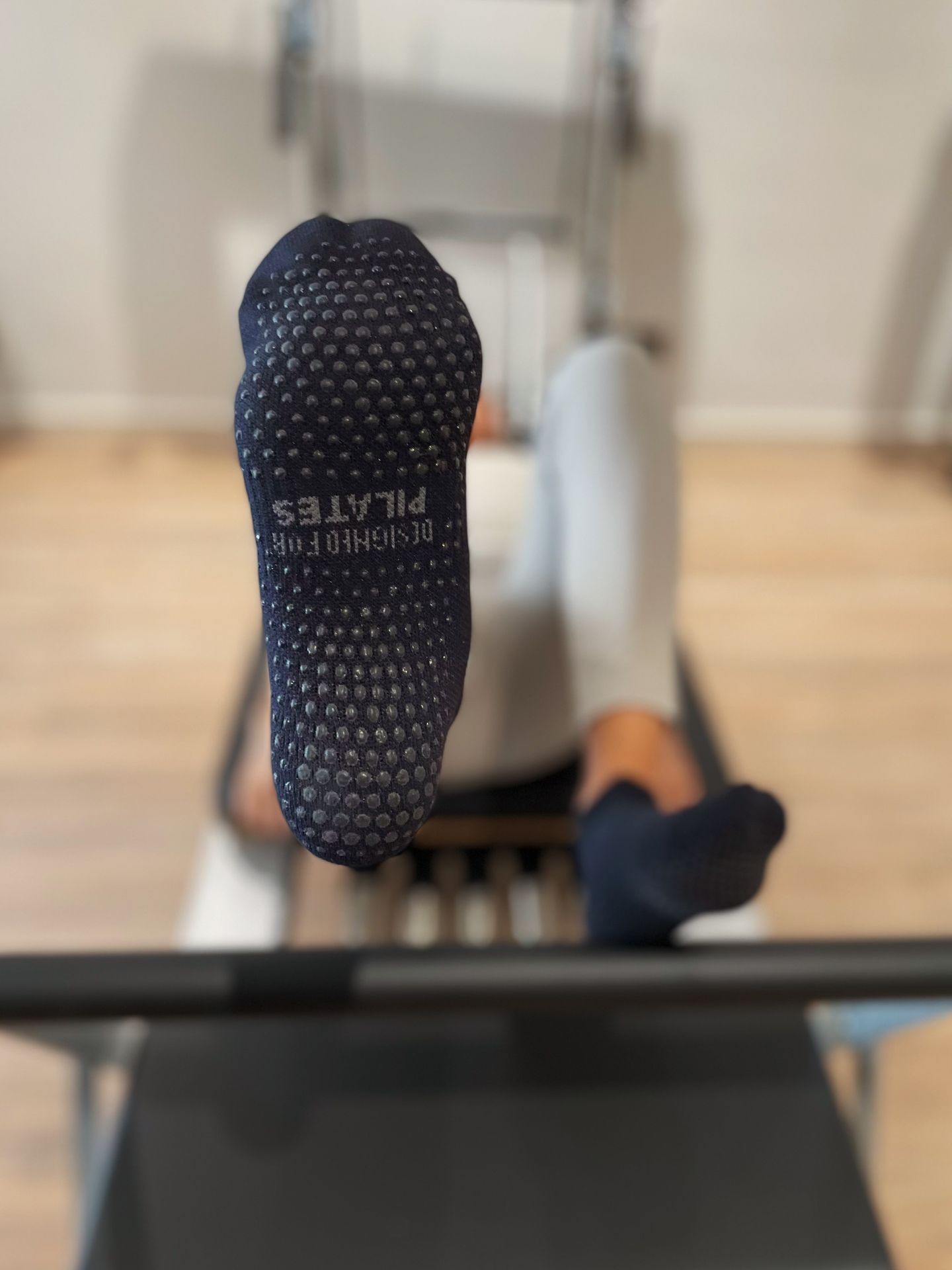 Close-up of a person's foot wearing grip socks during a Pilates workout on a reformer machine.